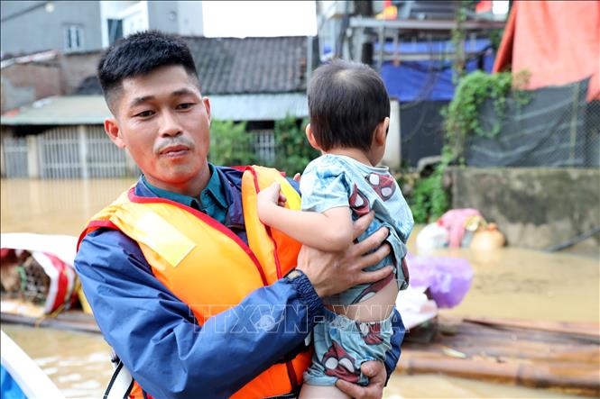 Lực lượng chức năng xã Tràng Định, tỉnh Lạng Sơn hỗ trợ đưa trẻ em từ vùng lũ đến nơi an toàn. Ảnh: Văn Đạt - TTXVN