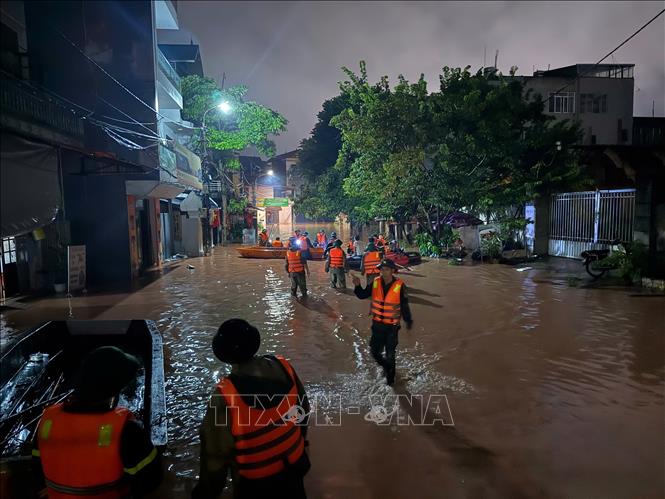 Lực lượng chức năng dùng thuyền đưa các hộ dân ra khỏi khu vực bị ngập tại phường Lương Văn Tri. Ảnh: Tiến Vĩnh – TTXVN 