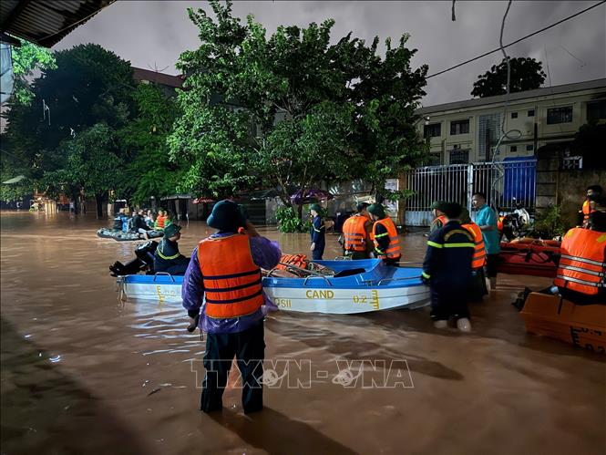 Lực lượng chức năng dùng thuyền di dời các hộ dân về nơi an toàn. Ảnh: Tiến Vĩnh – TTXVN 