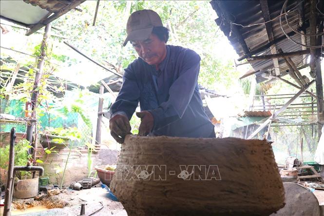 Ông Trần Dục tạo khuôn đất từ đất sét và trấu, sau đó nung chín khuôn để dùng làm dụng cụ đúc đồng. Ảnh: Đinh Hương - TTXVN