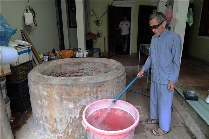 Ông Nguyễn Văn Mích ở Tam Xuân, Đà Nẵng, bên dòng nước mát được bơm lên từ giếng Chăm cổ. Ảnh: Đỗ Trưởng – TTXVN