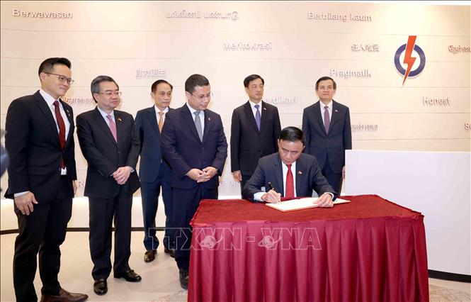 Thường trực Ban Bí thư Trần Cẩm Tú viết sổ lưu niệm tại trụ sở Đảng Hành động Nhân dân Singapore. Ảnh: Phương Hoa - TTXVN