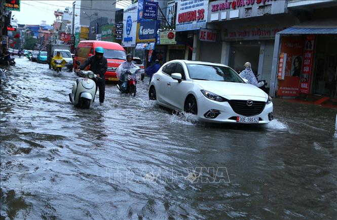 Các phương tiện nối đuôi từ từ di chuyển qua đoạn đường Trường Chinh, phường Nam Định bị ngập. Ảnh: Công Luật - TTXVN