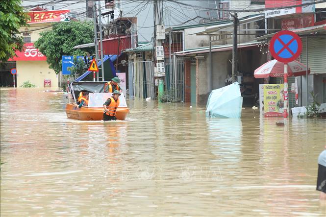 Lực lượng quân đội hỗ trợ đưa người dân ra khỏi vùng ngập lụt. Ảnh: Quang Duy – TTXVN

