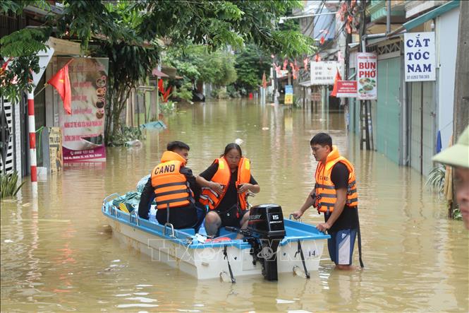 Lực lượng quân đội hỗ trợ người dân di chuyển trong vùng ngập lụt. Ảnh: Quang Duy – TTXVN
