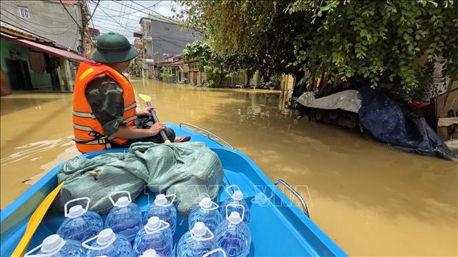 Lực lượng quân đội vận chuyển nước uống tới khu vực bị mưa lũ cô lập. Ảnh: Quang Duy - TTXVN
