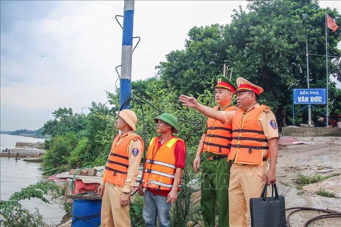 Lực lượng Cảnh sát đường thủy phối hợp Công an xã Bát Tràng kiểm tra tình hình tại bến phà Văn Đức khi nước sông Hồng dâng cao. Ảnh: Trung Nguyên - TTXVN