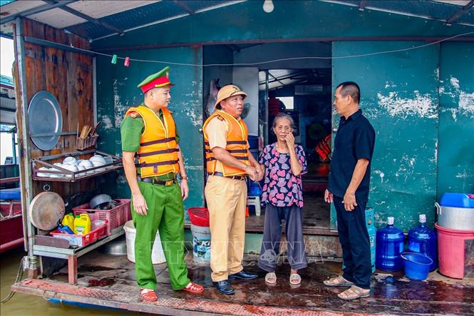Cán bộ Đội Cảnh sát đường thủy số 2 phối hợp Công an xã Bát Tràng thăm hỏi, hướng dẫn các hộ dân vạn chài chủ động phòng tránh rủi ro khi nước sông Hồng dâng cao. Ảnh: Trung Nguyên - TTXVN