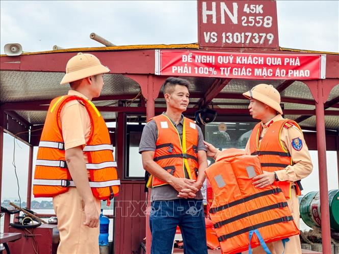Cảnh sát đường thủy hướng dẫn người quản lý phương tiện thực hiện quy định bảo đảm an toàn cho hành khách tại bến phà Văn Đức. Ảnh: Trung Nguyên - TTXVN