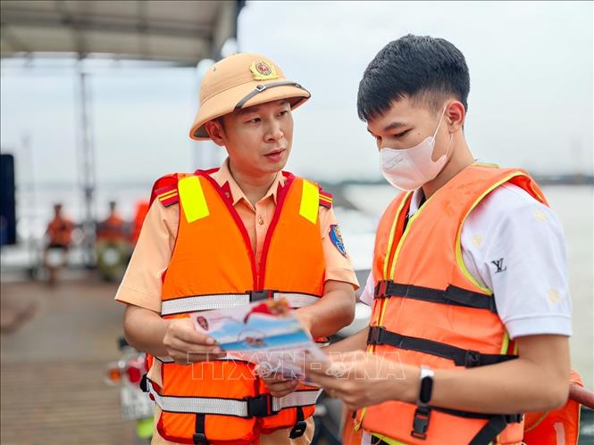 Cảnh sát đường thủy phát tài liệu, tuyên truyền quy định bảo đảm an toàn cho người dân khi tham gia giao thông đường thủy. Ảnh: Trung Nguyên - TTXVN