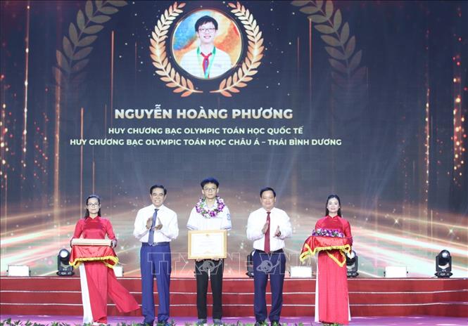 Lãnh  đạo tỉnh Nghệ An trao thưởng cho em Nguyễn Hoàng Phương, học sinh Trường THPT Chuyên Phan Bội Châu đạt Huy chương Bạc tại kỳ thi Olympic quốc tế và khu vực châu Á - Thái Bình Dương về môn Toán. Ảnh: Bích Huệ - TTXVN