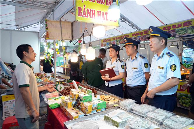Cán bộ Quản lý thị trường kiểm tra việc niêm yết giá công khai tại các gian hàng. Ảnh: Hữu Quyết - TTXVN