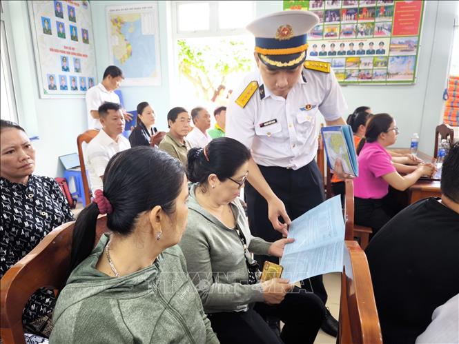 Phát tờ rơi tuyên truyền cho ngư dân xã Tân Thủy, tỉnh Vĩnh Long. Ảnh: Huỳnh Phúc Hậu - TTXVN