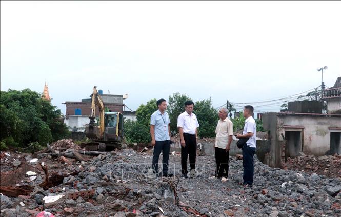 Đại diện chính quyền xã Hưng Phú, tỉnh Hưng Yên, trao đổi với ông Phạm Văn Tá (thứ hai từ phải sang) trong quá trình tháo dỡ công trình, giải phóng mặt bằng tại nút giao đường 221A. Ảnh: Đinh Văn Nhiều – TTXVN