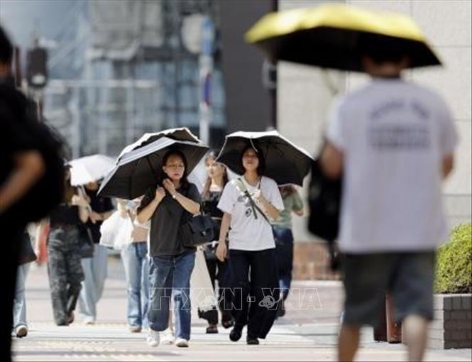 Người dân che ô tránh nắng nóng tại Fukuoka, Nhật Bản, ngày 26/8/2026. Ảnh: Kyodo/TTXVN phát