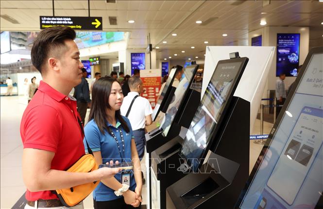 Nhân viên sân bay Nội Bài hỗ trợ hành khách làm thủ tục qua hình thức quét sinh trắc học để giảm thiểu thời gian xếp hàng chờ đến lượt tại quầy, sáng 28/8. Ảnh: Quốc Khánh - TTXVN