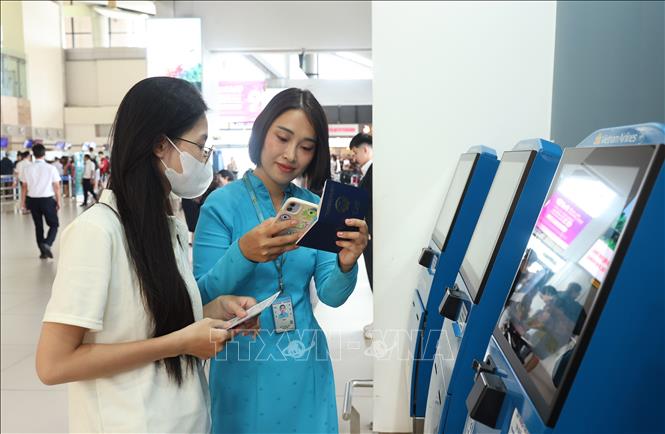 Nhân viên Hãng hàng không quốc gia Việt Nam (Vietnam Airlines) nhiệt tình hướng dẫn hành khách vào quầy làm thủ tục check-in tự động tại sân bay Nội Bài, sáng 28/8. Ảnh: Quốc Khánh - TTXVN