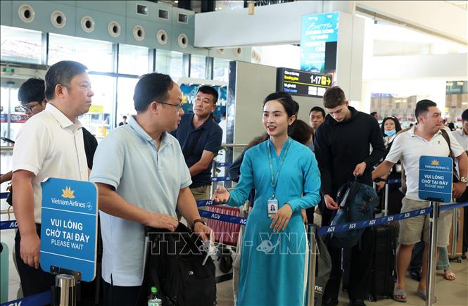 Nhân viên Hãng hàng không quốc gia Việt Nam (Vietnam Airlines) nhiệt tình hướng dẫn hành khách vào quầy làm thủ tục check-in, sáng 28/8. Ảnh: Quốc Khánh - TTXVN
