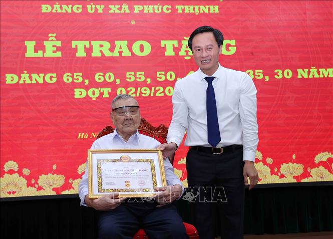 Đồng chí Hoàng Hải Đăng, Bí thư Đảng uỷ, Chủ tịch HĐND xã Phúc Thịnh (Hà Nội) trao Huy hiệu 65 năm tuổi Đảng cho đảng viên Hoàng Văn Quyết. Ảnh: Văn Điệp - TTXVN