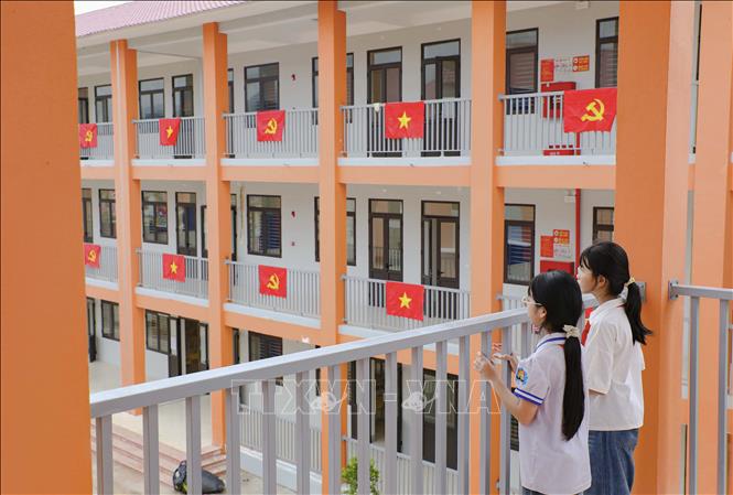 Học sinh trò chuyện trên hành lang, phía sau là những dãy phòng học được trang trí cờ Đảng, cờ Tổ quốc. Ảnh: Xuân Tư - TTXVN