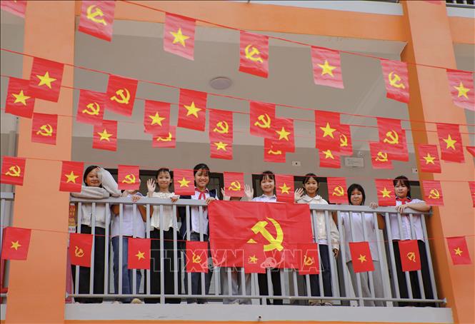 Học sinh Trường Phổ thông nội trú Tiểu học và THCS Sam Mứn tươi vui bên những lá cờ Đảng, cờ Tổ quốc được trang trí trên hành lang. Ảnh: Xuân Tư - TTXVN