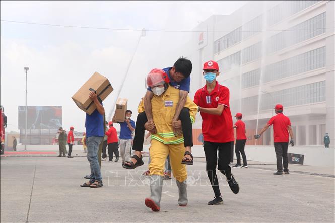 Lực lượng công nhân lao động tại chỗ và Hội Chữ Thập đỏ TP. Hồ Chí Minh thực hiện các biện pháp  cứu người bị nạn trong vụ cháy. Ảnh: Thanh Vũ - TTXVN