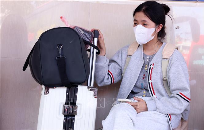 Một bạn sinh viên mệt mỏi chờ lên xe về quê tại bến xe Giáp Bát. Ảnh: Quốc Khánh - TTXVN