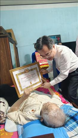 Trưởng ban Chính sách, chiến lược Trung ương Nguyễn Thanh Nghị trao huy hiệu 80 tuổi Đảng cho đồng chí Huỳnh Thị Cạnh, đảng viên Chi bộ Tổ dân phố 5, Đảng bộ phường Quy Nhơn, tỉnh Gia Lai. Ảnh: Sỹ Thắng - TTXVN