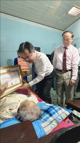 Trưởng ban Chính sách, chiến lược Trung ương Nguyễn Thanh Nghị trao huy hiệu 80 tuổi Đảng cho đồng chí Huỳnh Thị Cạnh, phường Quy Nhơn, tỉnh Gia Lai. Ảnh: Sỹ Thắng - TTXVN
