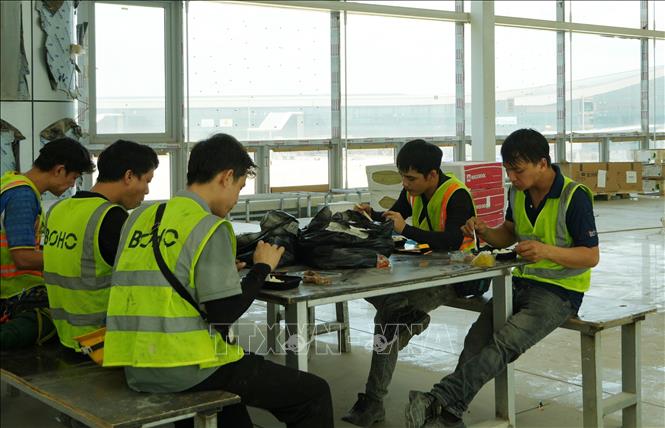 Người lao động tranh thủ giờ nghỉ ăn cơm trưa tại công trường sân bay Long Thành. Ảnh: Công Phong - TTXVN