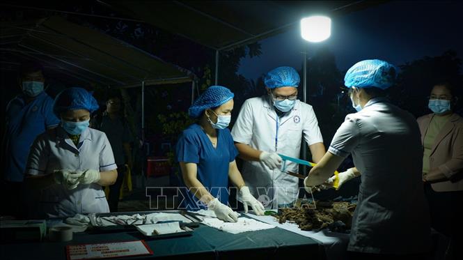 Cán bộ, nhân viên chuyên môn tỉnh Tây Ninh, khẩn trương lấy mẫu sinh phẩm hài cốt liệt sĩ trong điều kiện làm việc ban đêm. Ảnh: Minh Phú - TTXVN 