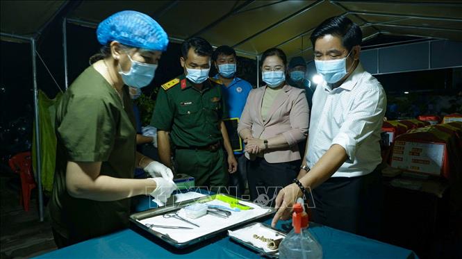 Dù đêm xuống, cán bộ, chiến sĩ và lực lượng chuyên môn vẫn khẩn trương thực hiện công tác lấy mẫu sinh phẩm hài cốt liệt sĩ tại Nghĩa trang Liệt sĩ Bến Lức. Ảnh: Minh Phú - TTXVN 