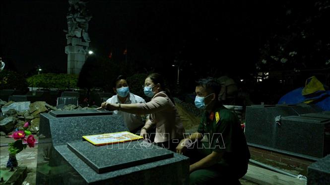 Các thành viên tổ công tác tranh thủ làm việc ban đêm, thực hiện lấy mẫu sinh phẩm tại Nghĩa trang Liệt sĩ Bến Lức. Ảnh: Minh Phú - TTXVN 