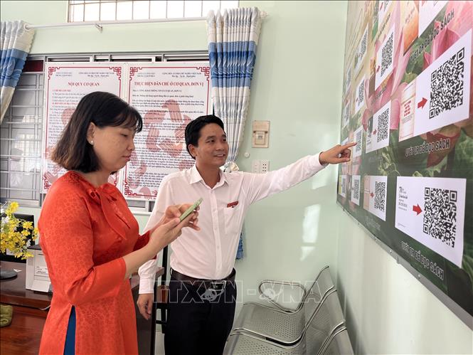 Chị Nguyễn Thị Đăng Khoa đến giải quyết thủ tục hành chính tại Trung tâm Phục vụ hành chính công xã Bình Hiệp, dành thời gian tìm hiểu thông tin về Chủ tịch Hồ Chí Minh. Ảnh: Đức Hạnh - TTXVN