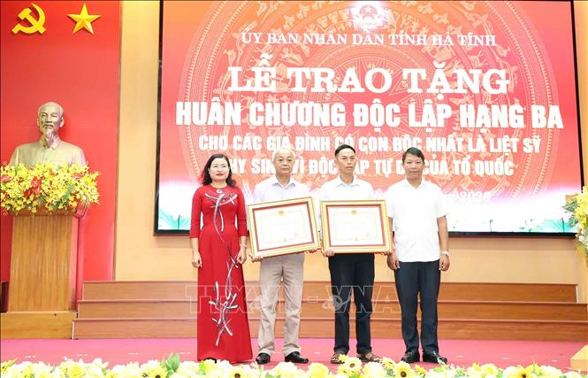 Phó Chủ tịch UBND tỉnh Hà Tĩnh Nguyễn Thị Nguyệt trao Huân chương Độc lập hạng Ba cho thân nhân các gia đình. Ảnh: Hữu Quyết - TTXVN