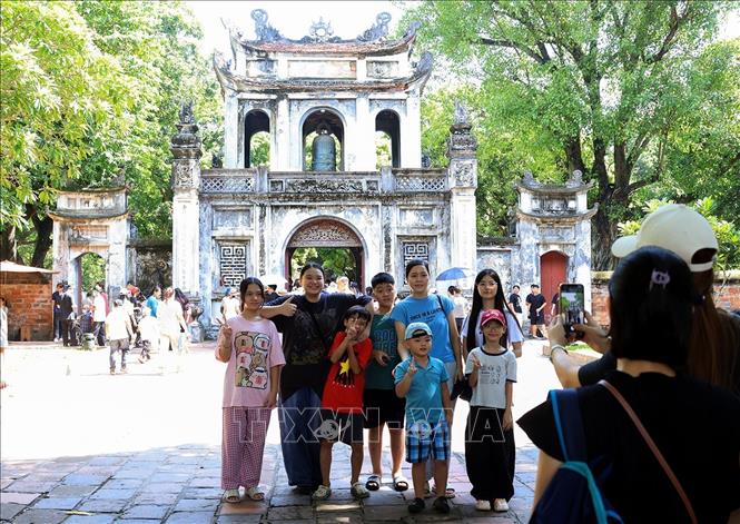 Một gia đình chụp ảnh lưu niệm trước cổng Văn Miếu - Quốc Tử Giám. Ảnh: Tuấn Anh - TTXVN