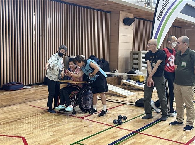 Một người khuyết tật đang được hướng dẫn trải nghiệm môn thể thao boccia. Ảnh: Nguyễn Tuyến - Pv TTXVN tại Nhật Bản