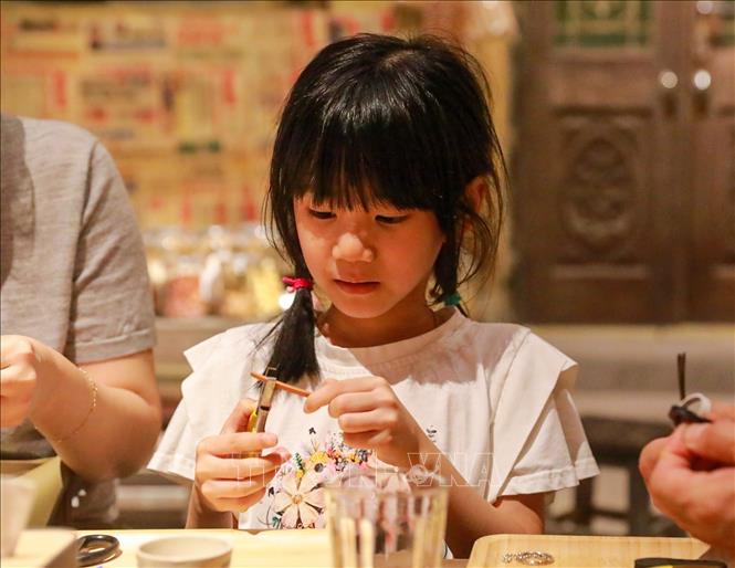 Khách tham quan trải nghiệm làm dép lốp. Ảnh: Khánh Hoà - TTXVN
