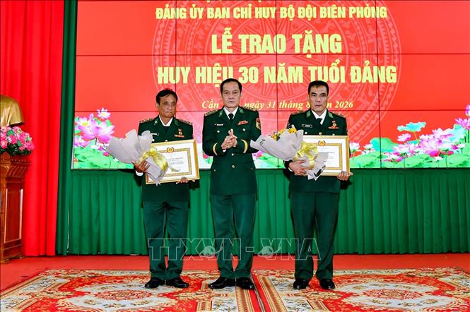 Đại tá Huỳnh Thanh Hùng, Bí thư Đảng ủy, Chính ủy Bộ đội Biên phòng thành phố Cần Thơ trao huy hiệu và tặng hoa chúc mừng cho 2 đồng chí nhận Huy hiệu 30 năm tuổi Đảng. Ảnh: Trung Kiên - TTXVN