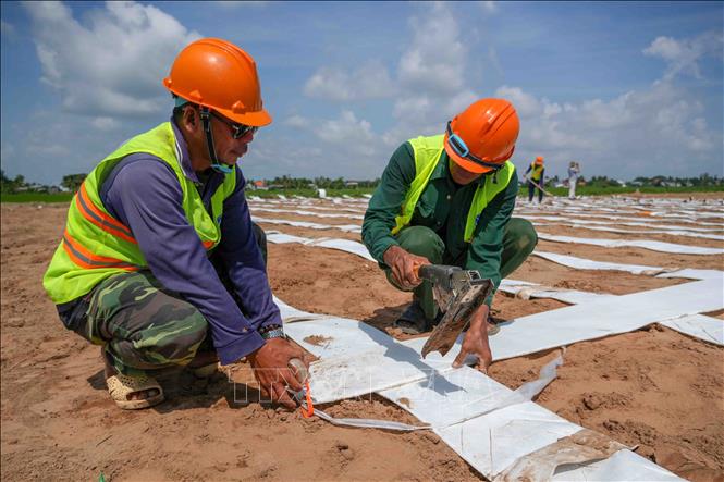 Công nhân Công ty TNHH Xây dựng Thương mại Ngọc Bảo trải bấc thấm để thoát nước cho nền đường ở gói thầu số 1, dự án thành phần 2, đoạn giáp ranh với tỉnh An Giang. Ảnh: Thanh Liêm - TTXVN