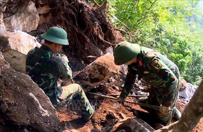 Đội quy tập hài cốt liệt sĩ dùng dụng cụ thô sơ cạy từng tảng đá, tìm kiếm hài cốt liệt sĩ tại Điểm cao 685. Ảnh: TTXVN phát