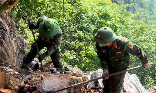Đội quy tập hài cốt liệt sĩ dùng dụng cụ thô sơ cạy từng tảng đá, tìm kiếm hài cốt liệt sĩ tại Điểm cao 685. Ảnh: TTXVN phát