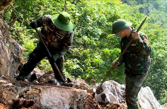 Đội quy tập hài cốt liệt sĩ dùng dụng cụ thô sơ cạy từng tảng đá, tìm kiếm hài cốt liệt sĩ tại Điểm cao 685. Ảnh: TTXVN phát