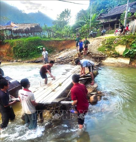 Người dân bản Na Ngân (xã Nga My, tỉnh Nghệ An) chung sức dựng lại cầu gỗ để nối lại 2 cụm dân cư trong bản. Trước đó, lũ dữ trên suối Nậm Ngân đã cuốn trôi cây cầu gỗ khiến bản Na Ngân bị chia cắt làm 2 cụm biệt lập. Ảnh: TTXVN phát  
