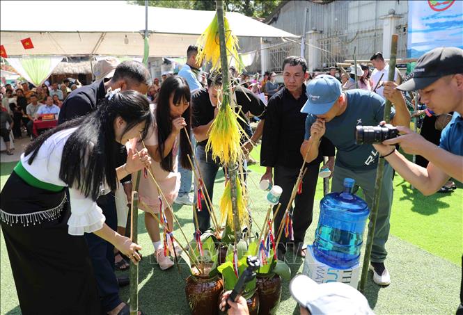 Du khách cùng người dân thưởng thức rượu cần một trong những sản phẩm được làm ra từ lúa mới. Ảnh: Quý Trung - TTXVN