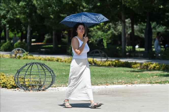 Người dân che ô tránh nắng nóng tại Madrid, Tây Ban Nha. Ảnh: THX/TTXVN phát