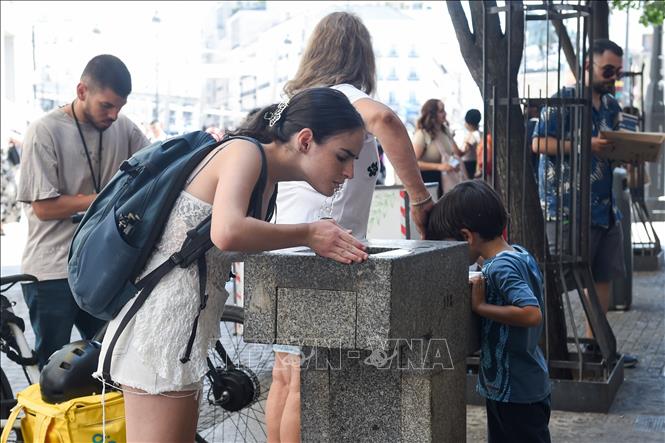 Người dân uống nước giải nhiệt trong ngày nắng nóng tại thủ đô Madrid, Tây Ban Nha. Ảnh: THX/TTXVN phát