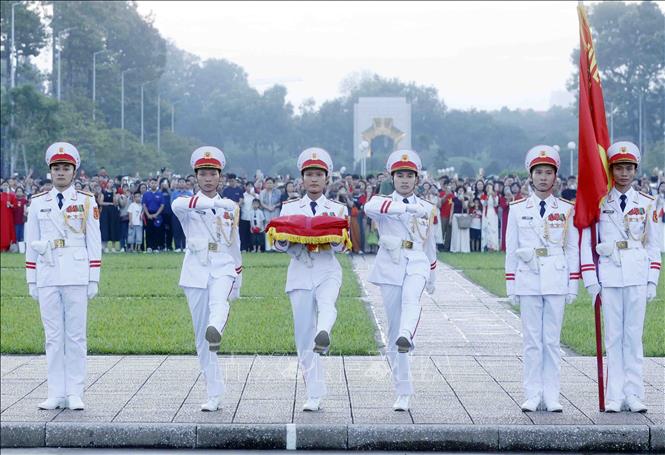 Ba chiến sĩ mang Quốc kỳ tiến về phía cột cờ chuẩn bị thực hiện nghi Lễ Thượng cờ. Ảnh: Phạm Kiên – TTXVN