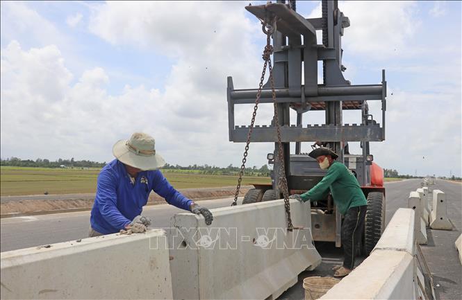 Công nhân thuộc Tổng Công ty Xây dựng Trường Sơn tăng ca làm xuyên lễ nhằm lắp đặt, hoàn thiện hệ thống dải phân cách. Ảnh: Công Mạo-TTXVN