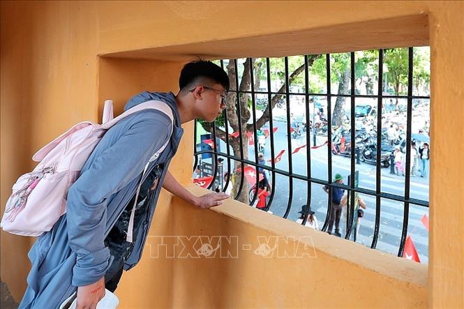 Qua ô cửa chòi canh từng dùng để kiểm soát nhà tù, các bạn trẻ hôm nay nhìn ra phố Hỏa Lò rực sắc cờ trong ngày Quốc khánh 2/9. Ảnh: Phạm Tuấn Anh - TTXVN